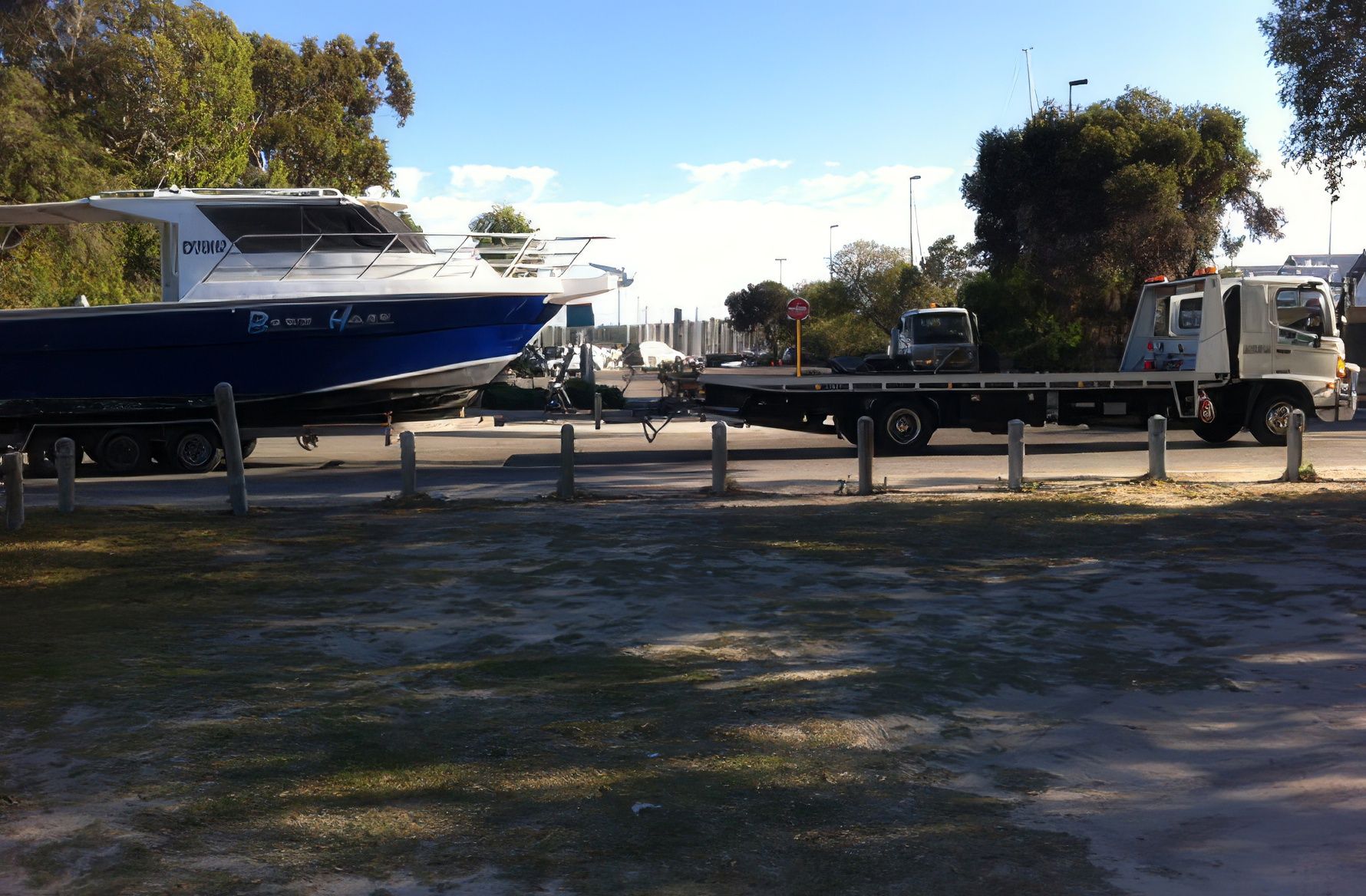 Boat on a trailer ready for vehicle transport next to a Quik Tow tilt tray truck in Perth